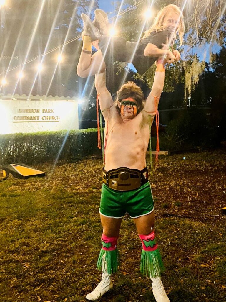 Lifting daughter over head in homemade Ultimate Warrior costume