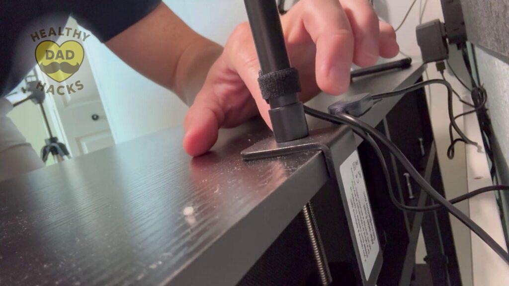 Close-up of Dad securing a metal bracket to dark wood with cables nearby, illuminated by the Best Gooseneck LED Desk Lamp.
