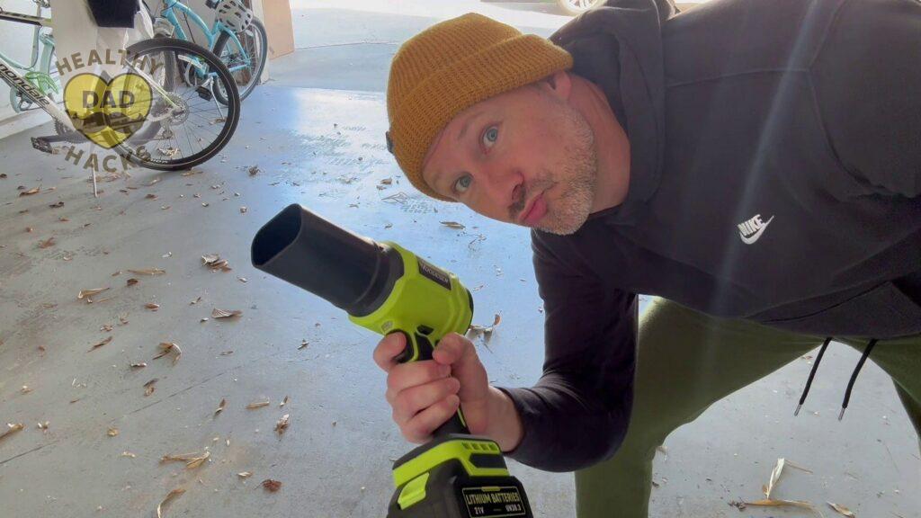 Dad using Yuquesen handheld cordless leaf blower to clean up garage